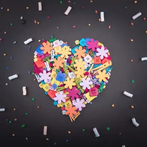 Heart made out of colorful buttons and clothespins with confetti on blackboard background to show how you can discover positive and creative ways to enjoy life with Rock Your Homeschool